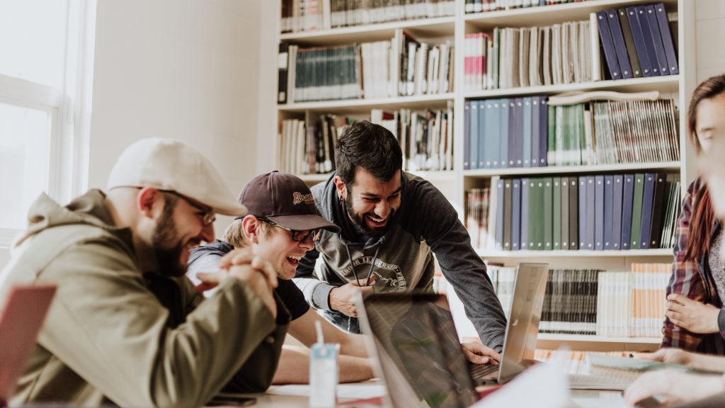 Three people looking at a computer and laughing.